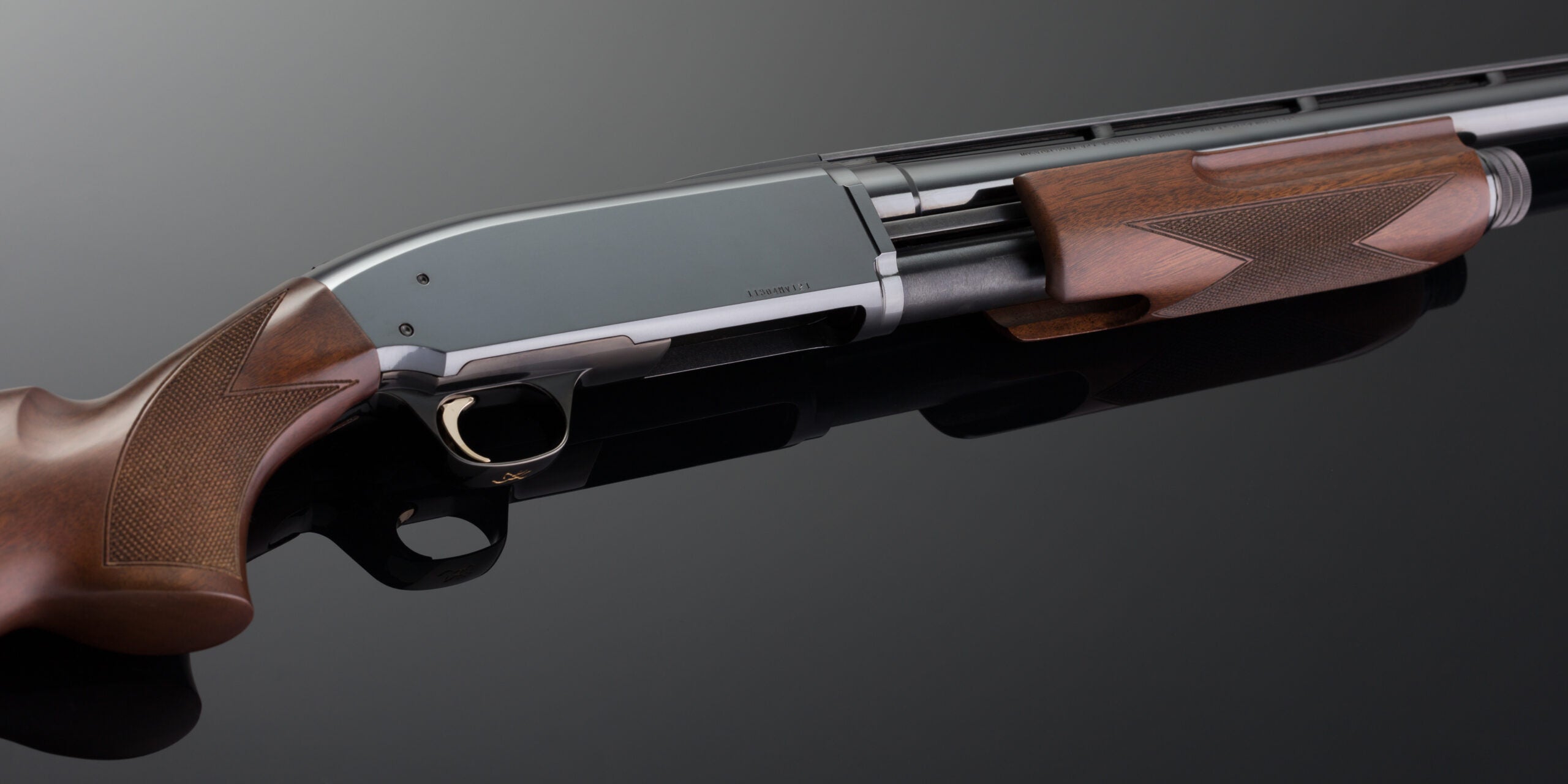 A Browning BPS shotgun lying on a glossy black surface.