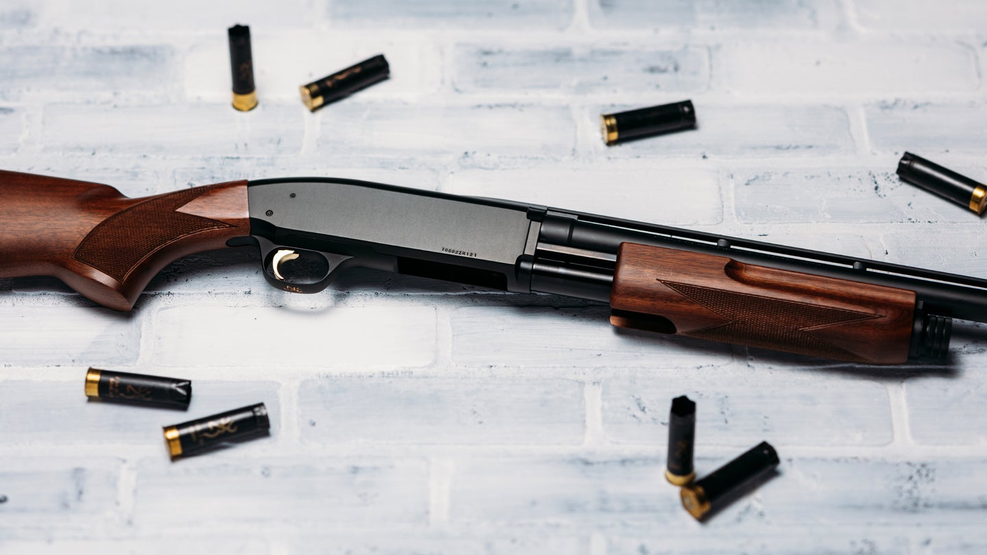 A Browning BPS shotgun lying on a white, brick surface with empty shells nearby.