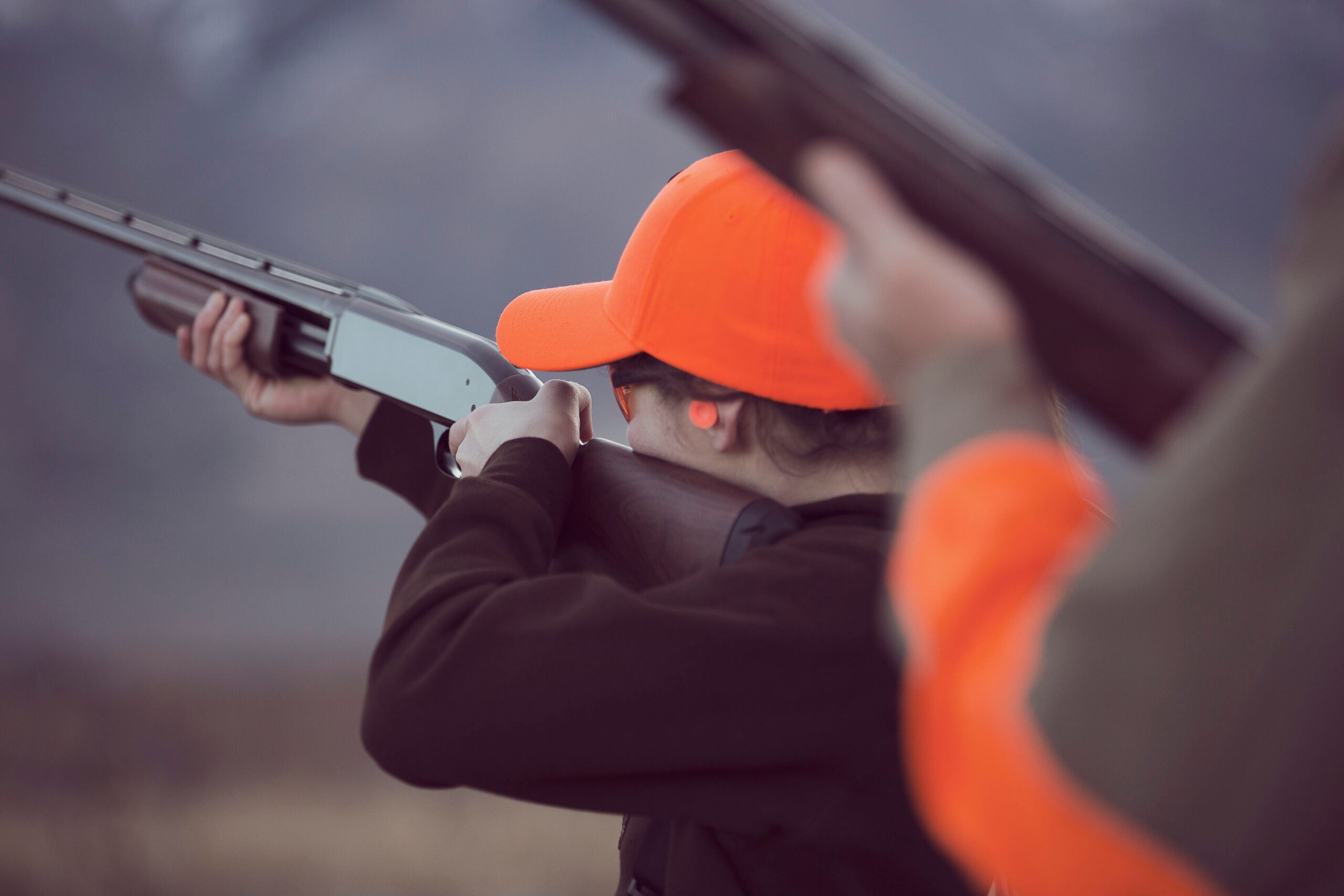 A young girl weather a hunter orange cap shoots a Browning BPS shotgun